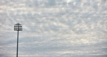 Two stadium lights under cloudy sky, background with copy cpace 