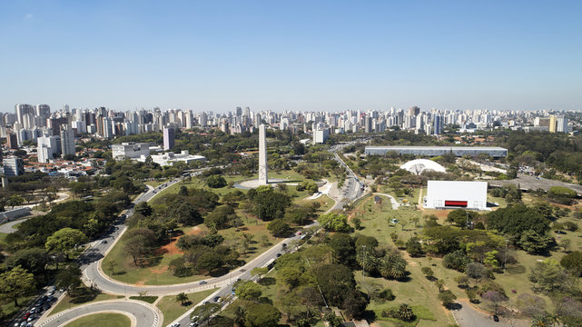 Aerial view of Ibirapuera park in Sao Paulo city, obelisk monument. Prevervetion area with trees and green area of Ibirapuera park. Office buildings and apartments in the background on a sunny day.