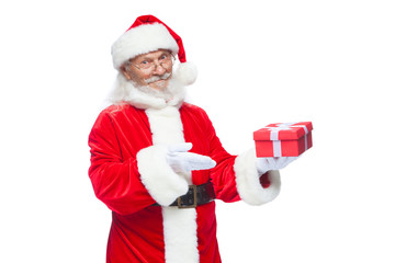 Christmas. Smiling Santa Claus in white gloves is holding a gift red box with a bow. Pointing at the gift. Isolated on white background.
