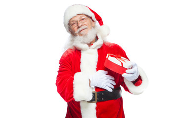 Christmas. Smiling Santa Claus in white gloves holds a red and white heart-shaped gift box with a red ribbon. Isolated on white background.