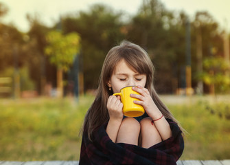 Cute girl outdoor with a cup of cocoa.
