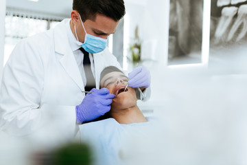 Young attractive man receiving a dental treatment. Close up shot.