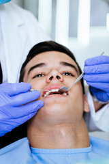 Young attractive man receiving a dental treatment. Close up shot.