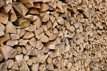 Background of stacked, dry chopped logs used for firewood.