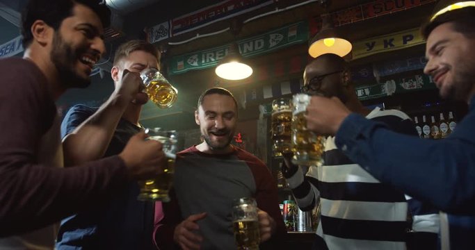 View from below on the mised races company doing cheers up with beer joyfully in the pub.