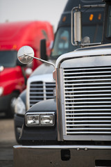 Fototapeta premium Part of front of big rig semi trucks cab with chrome grille and headlight on parking lot