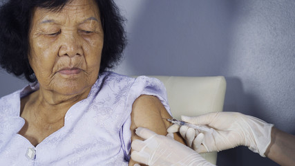 Doctor giving vaccine injection into senior woman