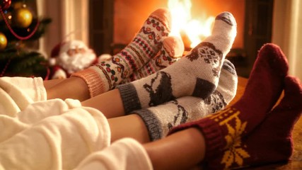 Closeup 4k video of family with child wearing warm wool socks lying by the fireplace on Christmas eve - Powered by Adobe
