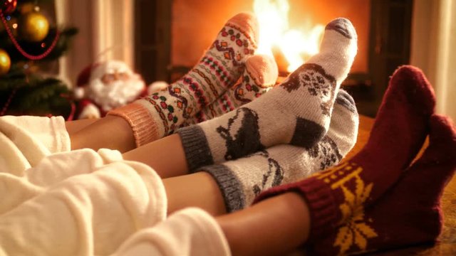 Closeup 4k video of family with child wearing warm wool socks lying by the fireplace on Christmas eve