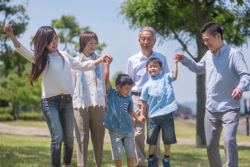 手を繋いで公園を歩く三世代家族