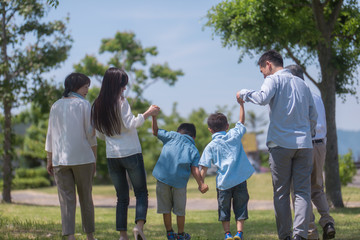 手を繋いで公園を歩く三世代家族の後ろ姿