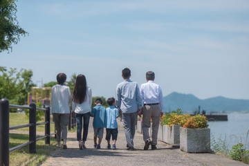 手を繋いで公園を歩く三世代家族の後ろ姿