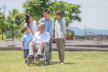 車椅子のシニア男性を囲む三世代家族