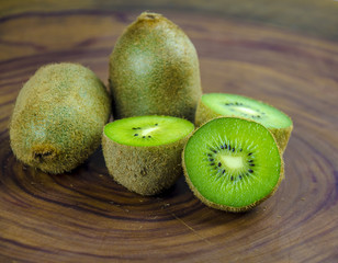Sliced fresh and juicy kiwi fruit halves on a wooden background.
