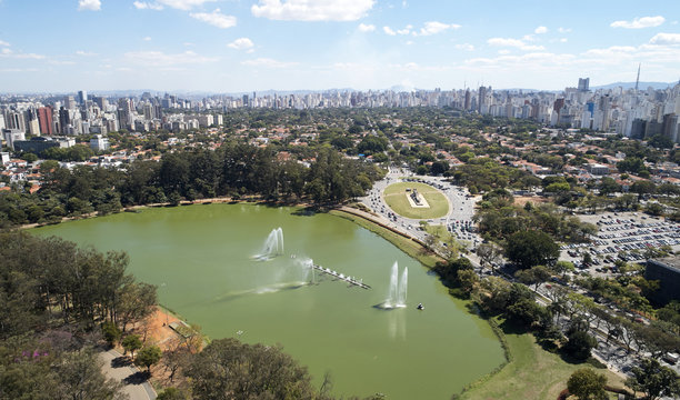 Aerial view of Ibirapuera park in Sao Paulo city, Monument to the Bandeiras. Prevervetion area with trees and lake of Ibirapuera park. Office buildings and residential district in the background.