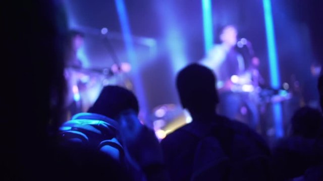 Mujer baila levantando las manos en vivo frente a su artista en concierto.