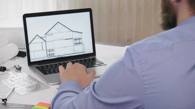 Architect working with blueprints on laptop computer