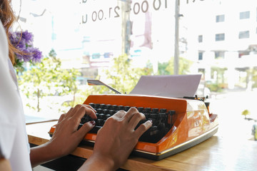 Woman is writing on an old typewriter.