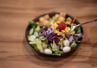 Bowl of Caesar Salad on the wooden table, close up