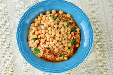 Close up dish fresh hummus and tahini dipped with olive oil, pepper, chickpea seed on white tablecloth rustic background. Overhead image of Hummus Traditional local Middle Eastern food.Copy space.