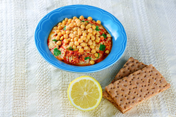 Close up dish fresh hummus and tahini dipped with olive oil, pepper,lemon, crispbread, chickpea seed on white tablecloth background.  Image of Hummus-Traditional local Israel and Middle Eastern food.