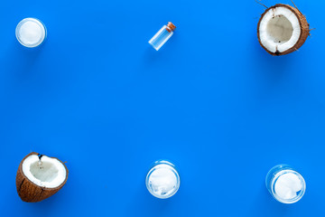 Cosmetics based on coconut oil. Oil in small bottle, cream, coconut pulp, half of coconut with shelf on blue background top view copy space pattern