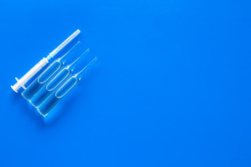 Flu vaccination concept. Syringe and ampoulie on blue background top view copy space