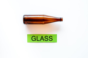 Types of matherial for reycle and reuse. Glass bottle near printed word glass on white background top view space for text