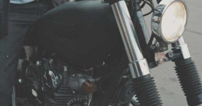 Motorbike handle grips. Close up the hand of the motorcyclist holds the trottle and pushes the brake lever. The biker inserts the key into the ignition lock and turns the bike.
