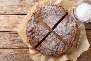 Swedish traditional dessert: kladdkaka chocolate sticky cake with powdered sugar close-up....