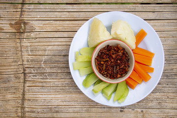 Chilli dip in cup with vegetables on bamboo floor