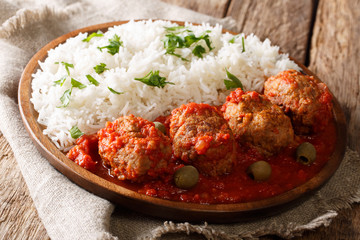 Greek food: Soutzoukakia baked meat balls in spicy tomato sauce served with rice close-up on a...