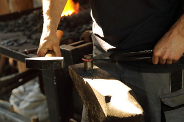 The blacksmith works with the metal on an anvil with a hammer