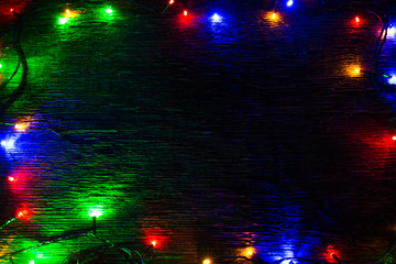 multicolored Christmas lights on a wooden background