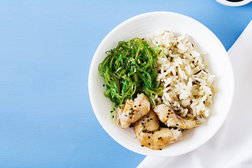 Japanese food. Bowl of rice, boiled white fish and wakame chuka or seaweed salad.  Top view. Flat...