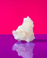 Sweet sugar in a crystal on a doutone pink -violet background with reflection.