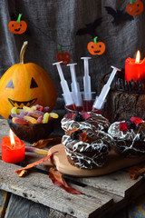 Halloween trick or treat party. Funny delicious sweets and pumpkin on wooden background - muffins, cupcakes, juice, jellies, candy.