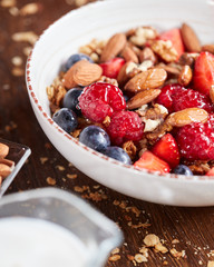 Fresh berries, almonds, oatmeal and granola in a plate with milk on a wooden background. Healthy food