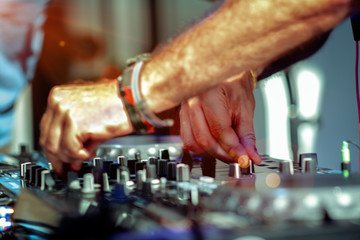 hand or fingers of DJ is rhythm music with Controller and mixer. DJ is playing the song at the party, adjusting the music with the controller. The fun of music and light colors, Music & Event