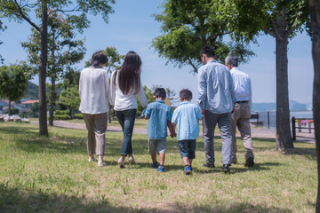 公園で手を繋ぎ歩く三世代家族