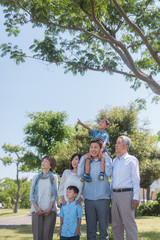 公園で息子を肩車するお父さんと三世代家族