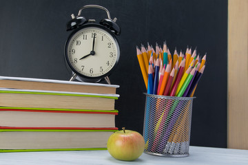 on the table a stack of books with an alarm clock on top, a snack break