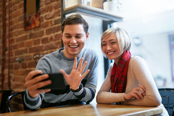 Couple Using On Phone In Cafe For Video Calling Or Taking Photos