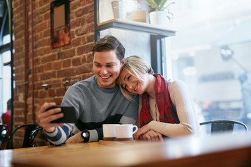 Couple Using On Phone In Cafe For Video Calling Or Taking Photos