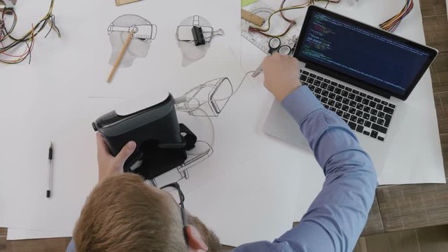 Software engineer plugs in VR headset and checks the code