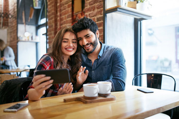 Couple Using On Phone In Cafe For Video Calling Or Taking Photos