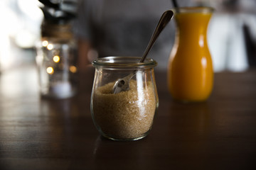 Brown sugar in glass jar and orange fresh juice on wooden table