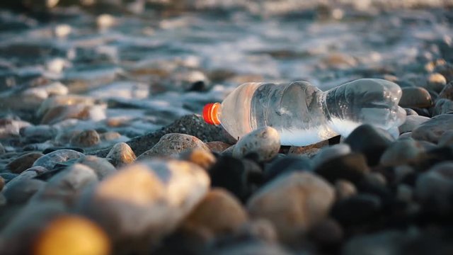 Selective Focus On Plastic Water Bottle, Sea Waves At The Background (Sea And Coastal Pollution)