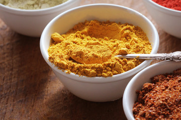 Turmeric powder.Various colorful spices on wooden table in bowls . Food and cuisine ingredients.