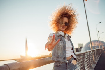 Young stylish woman with very lush hair show victory sign